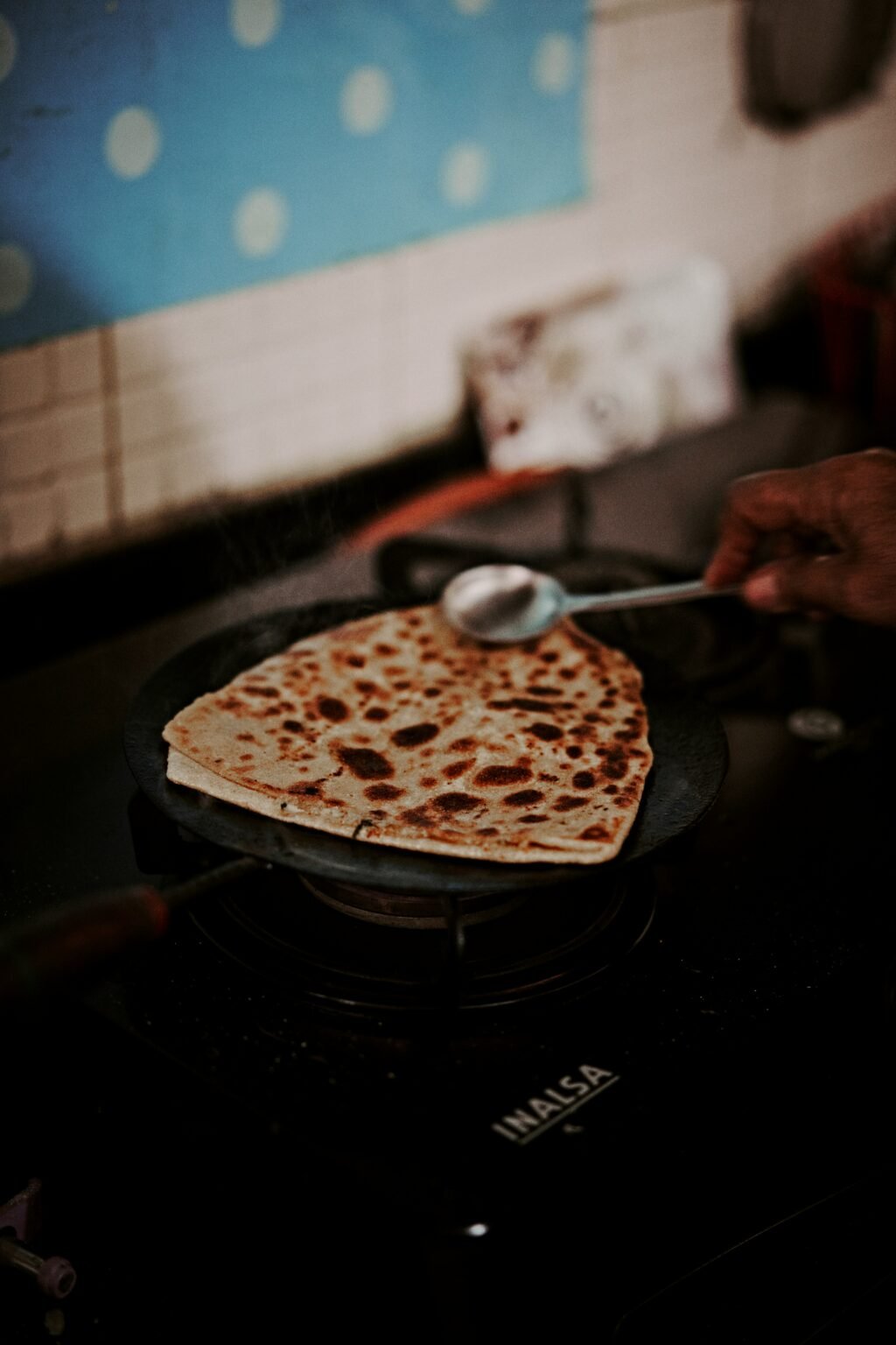 Paratha cooking on a hot tawa with ghee