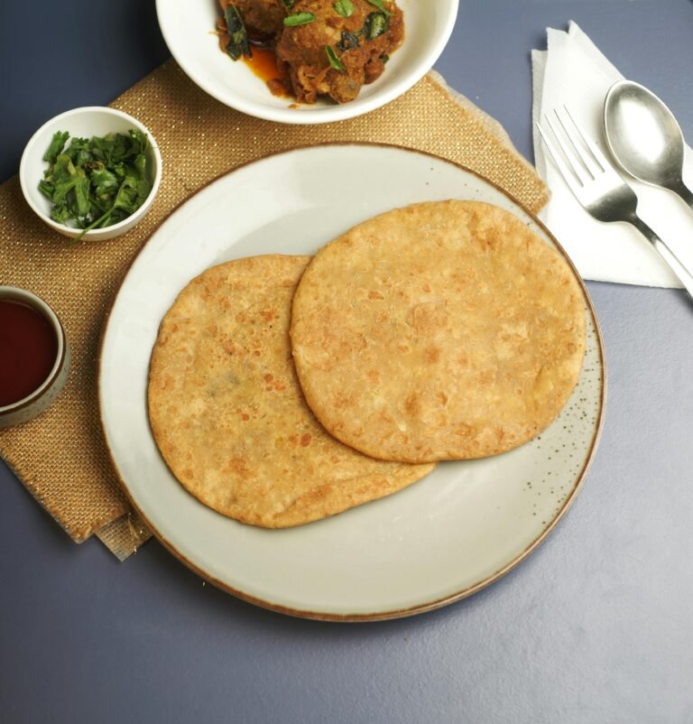 Fresh parathas plated with chutney and curry bowls