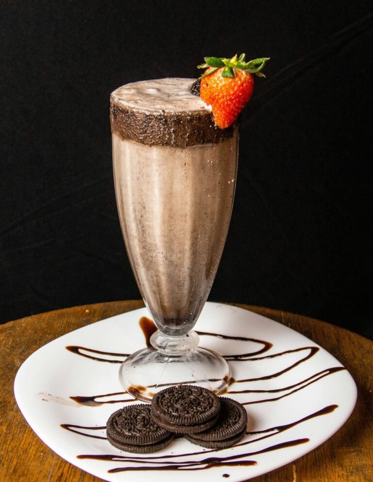 Chocolate milkshake in a tall glass with strawberry garnish